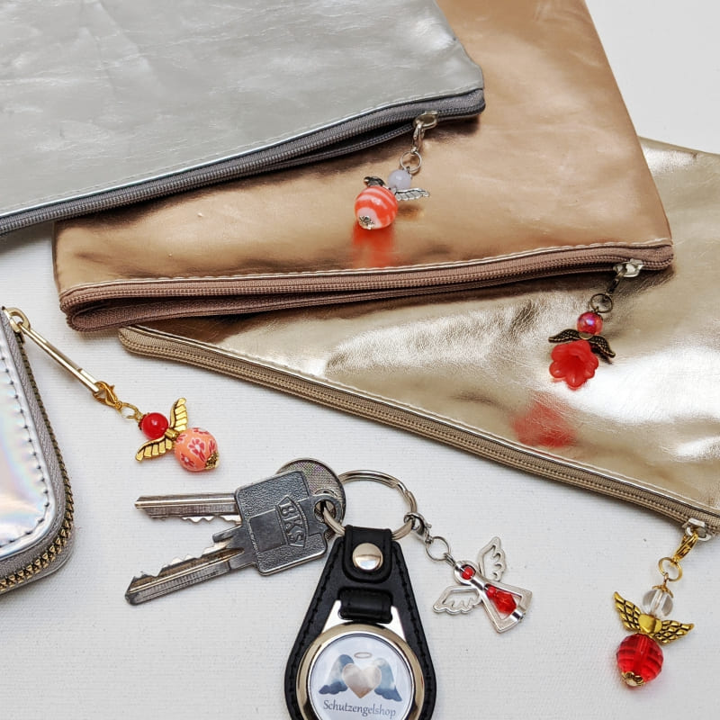 verschiedene rote Schutzengel dekoriert an Reißverschlüssen und an einem Schlüsselbund verschiedene rote Schutzengel dekoriert an Reißverschlüssen und an einem Schlüsselbund